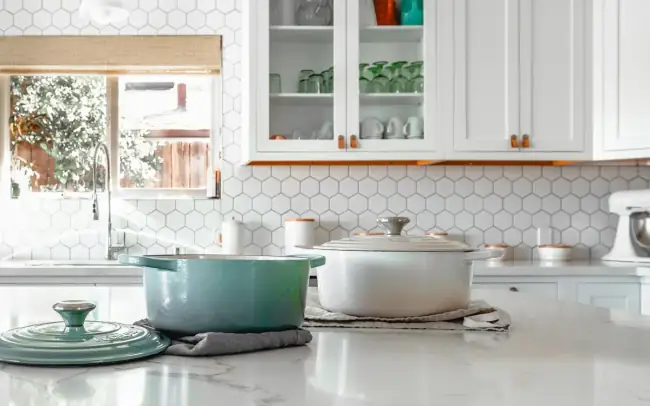 Modern renovated kitchen with white cabinetry, marble counters and tile backsplash