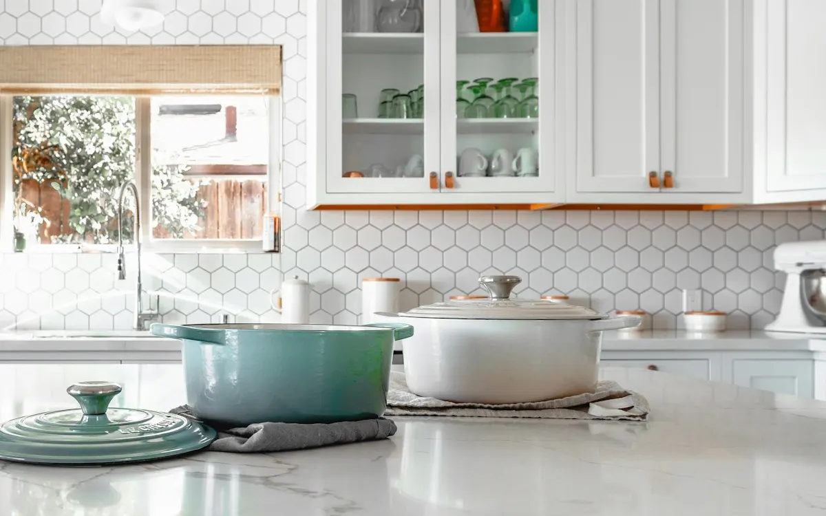 Modern renovated kitchen with white cabinetry, marble counters and tile backsplash
